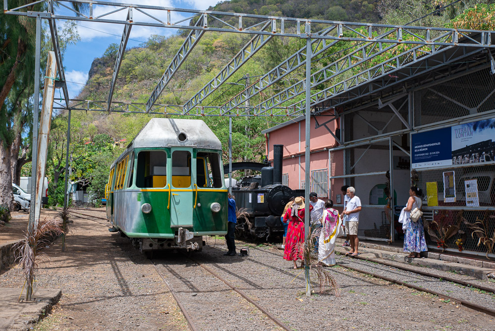 Visite ti train lontan exposée avec des visiteurs autour.