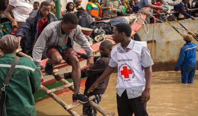 Un volontaire de la croix rouge aide des personnes à descendre des bateaux. Photo PIROI